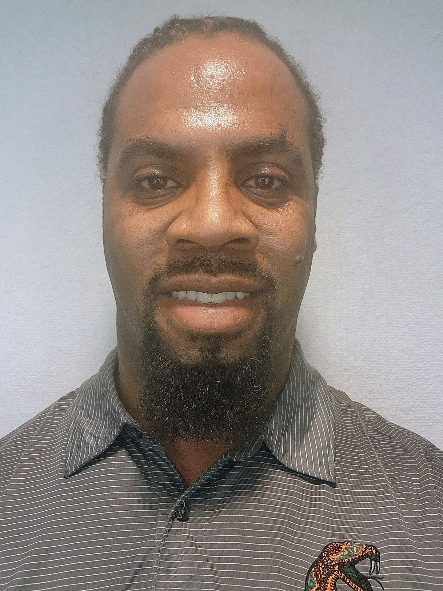 Person wearing a striped gray shirt with an embroidered snake design on the left side.